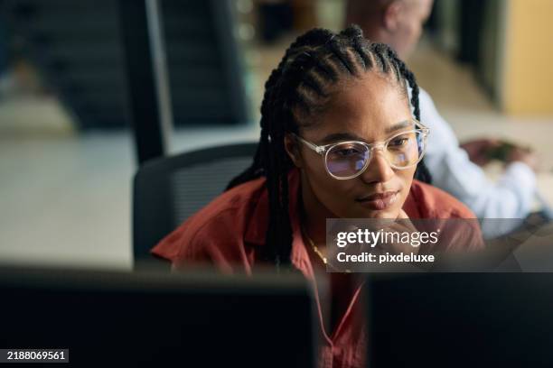 jovem programadora focada em seu trabalho, codificando em monitores duplos em um ambiente de escritório moderno - examinar - fotografias e filmes do acervo