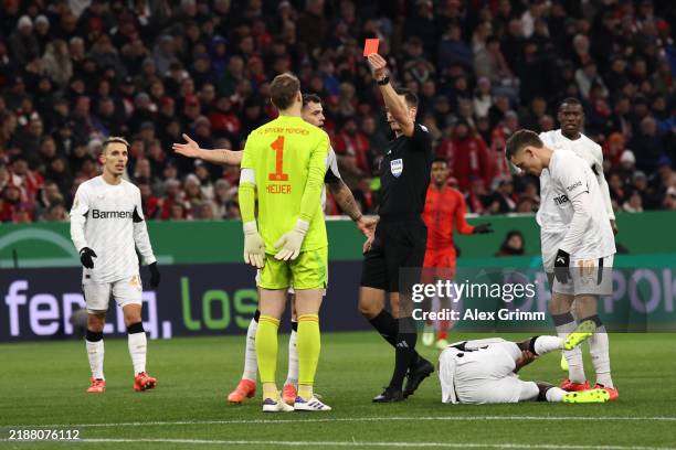 Referee Harm Osmers shows a red card to Manuel Neuer of Bayern Munich during the DFB Cup round of 16 match between FC Bayern München and Bayer 04...