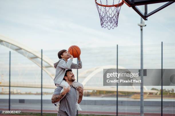 together we aim: father supporting son’s basketball dream - basketball stock pictures, royalty-free photos & images