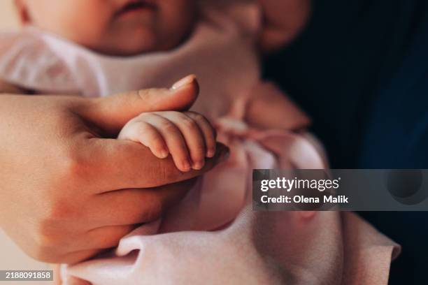 baby's hand in mother's embrace - adopción fotografías e imágenes de stock