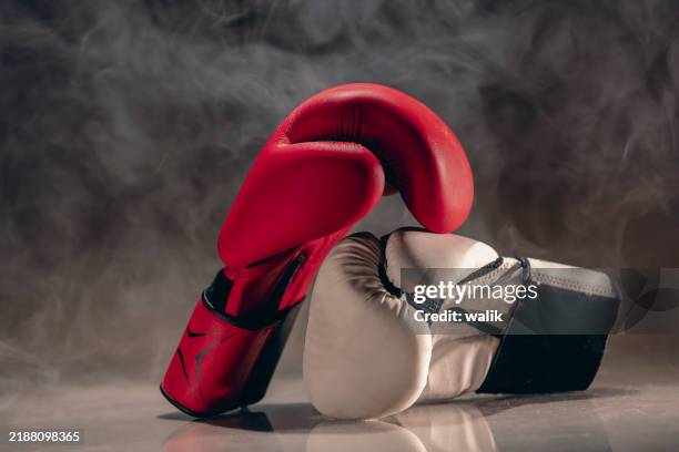 un par de guantes de boxeo rojos sobre fondo oscuro. - guante de boxeo fotografías e imágenes de stock