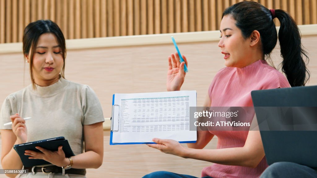 Asian Female Professional Team Presentation with Data Analysis in a Casual Modern Workspace