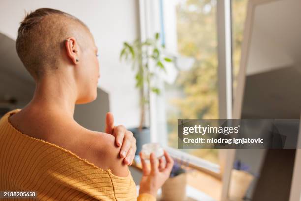 frau, die hormoncreme auf die schulter aufträgt - östrogen stock-fotos und bilder