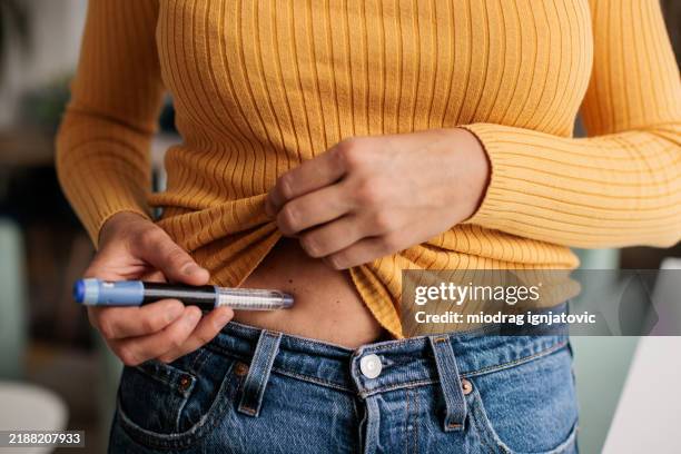 mujer inyectando medicamentos de fiv en el estómago - fecundación in vitro fotografías e imágenes de stock