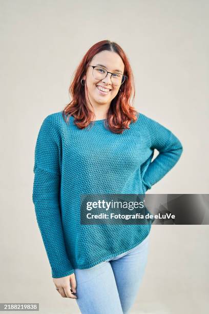 young woman with glasses and teal sweater smiling at camera - com as mãos nas cadeiras imagens e fotografias de stock