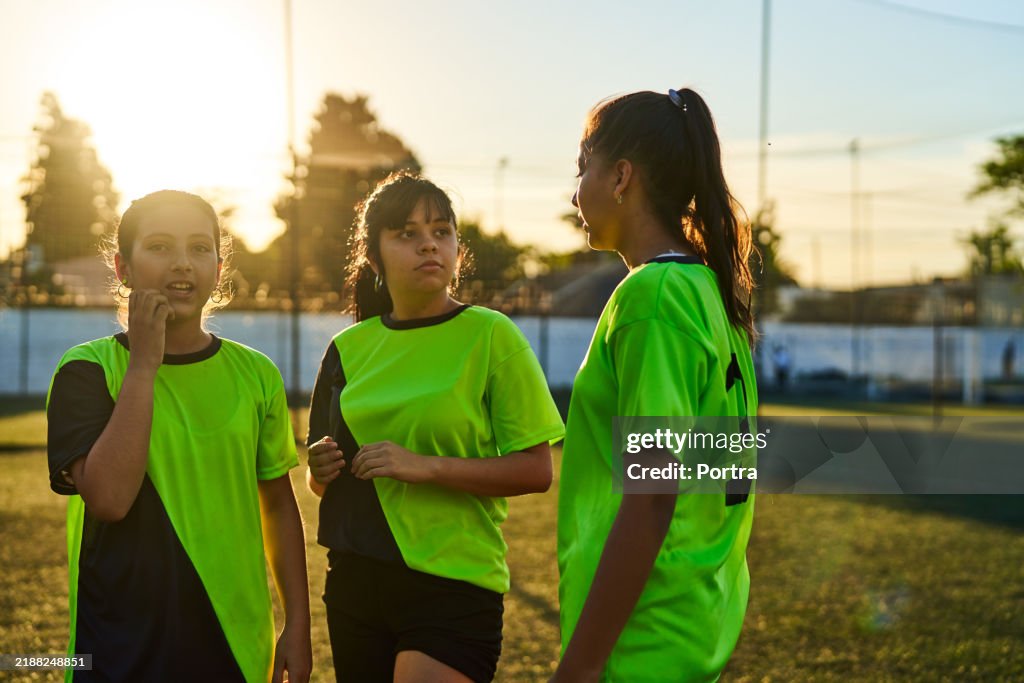 Girls Soccer team standing at sports court on sunny day