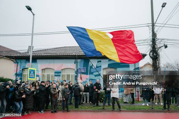 Man waves a Romanian flag in front of a closed voting station where presidential candidate Calin Georgescu was supposed to vote on December 8, 2024...