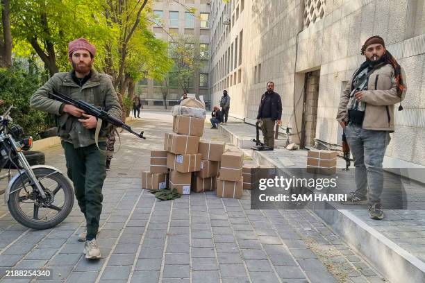 Anti-government fighters secure boxes of money after preventing looters outside the central bank in Damascus on December 8, 2024. Islamist-led rebels...
