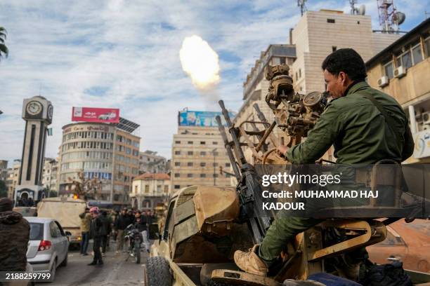 Syrian rebel fighter fires rounds as people celebrate near the New Clock Tower in the central city of Homs on December 8 after rebel forces entered...