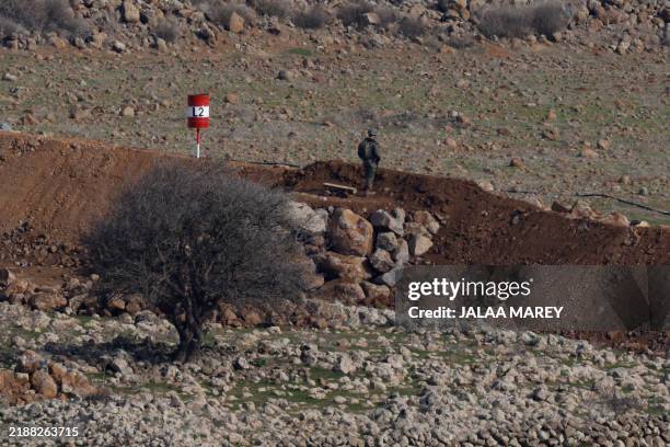 Picture taken from the Israeli-annexed Golan Heights shows an Israeli soldier standing next to land cleared by Israeli forces around the...