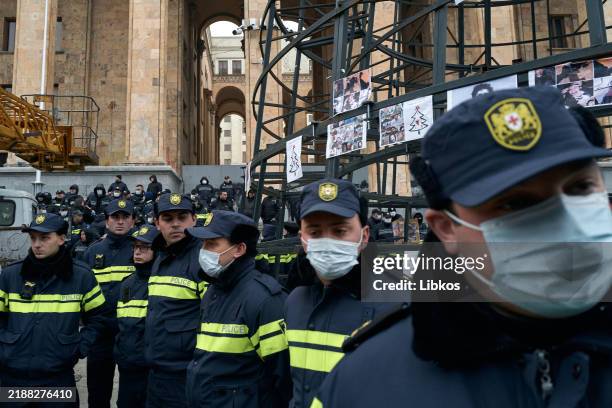 Police officers stand guard by the Parliament building, where municipal workers set up a New Year's tree, after it was covered it with photos of...