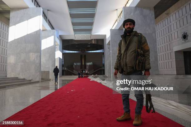 Fighters walk in the Syrian presidential palace in Damascus' Mount Qasyoun on December 8 after Islamist-led rebels declared that they have taken the...
