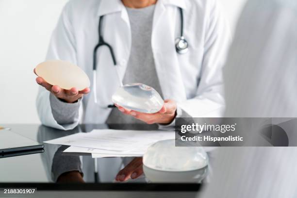 plastic surgeon comparing two types of breast implants - implante mamário imagens e fotografias de stock