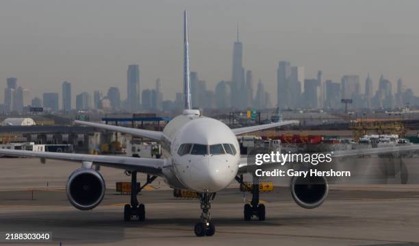 United Airlines airplane proceeds to a gate at Newark Liberty International Airport in front of the skyline of lower Manhattan and One World Trade...