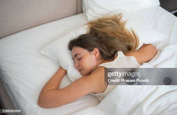 caucasian woman sleeping in bed - auf dem bauch liegen stock-fotos und bilder