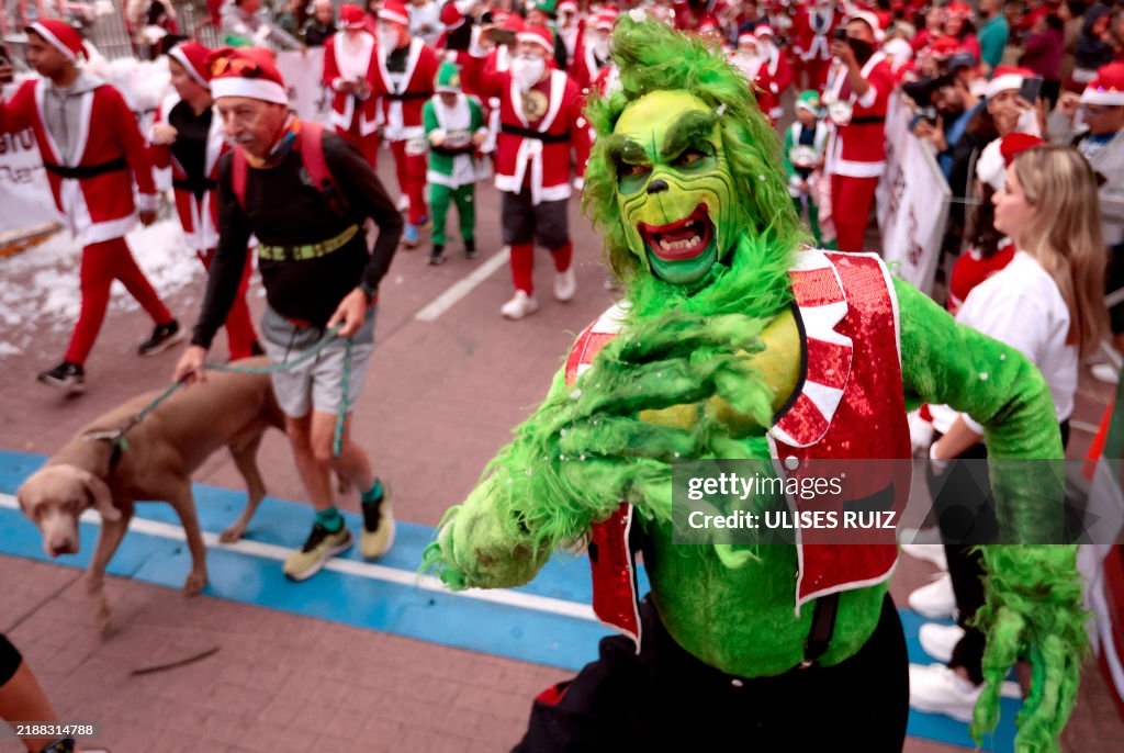 Mx Santa A Grinch character gestures next to runners dressed as Santa Claus ...