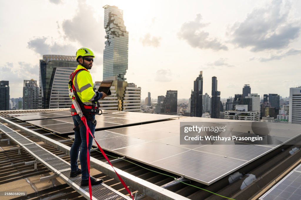 Engineer Inspecting Solar Panels On Urban Rooftop Against City Skyline