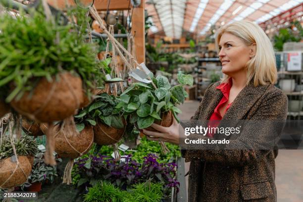 senior woman shopping for plants and flowers at a garden centre - tuincentrum stockfoto's en -beelden
