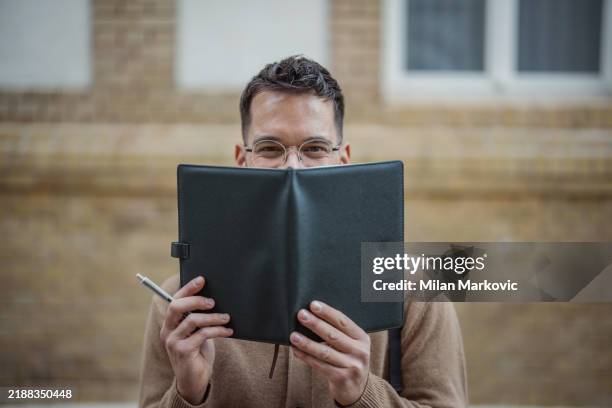 student peeking out from behind notebook - modern marvel stock pictures, royalty-free photos & images