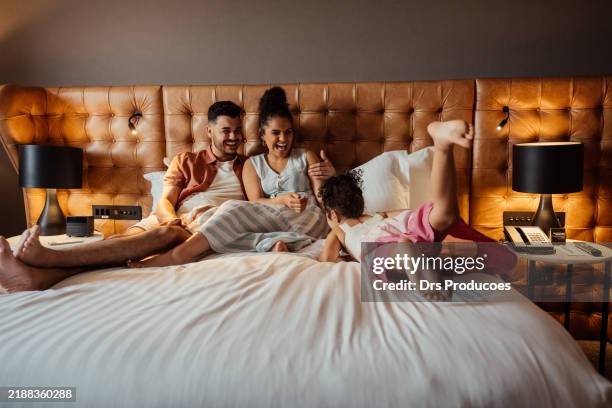 couple playing with daughter on hotel bed - hotel suite stock pictures, royalty-free photos & images