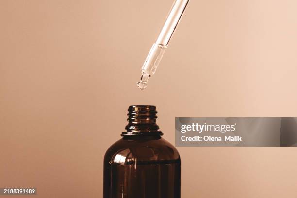 glass dropper bottle with droplet for skincare and aromatherapy oils. demonstrating mocha color - trendy color of the year 2025 - dropper bottle stock pictures, royalty-free photos & images