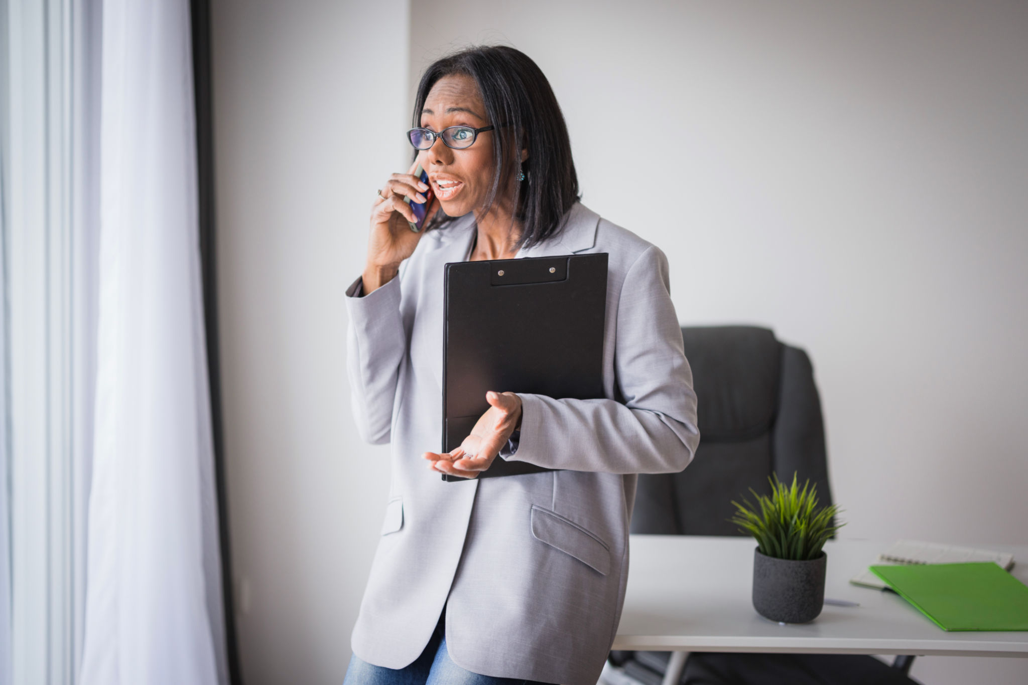 Displeased business woman with documents having a phone conversation Displeased business woman with documents having a phone conversation
