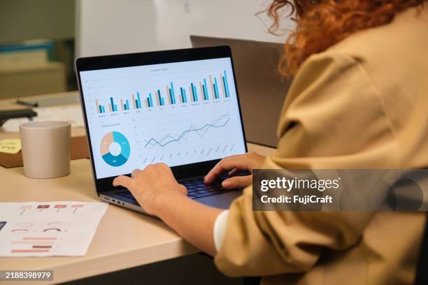 businesswoman analyzing financial charts on laptop in office - financial report stock pictures, royalty-free photos & images