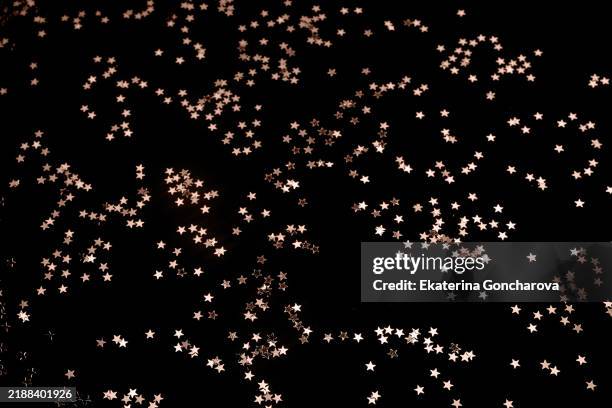 rose gold star confetti scattered on black background - scattered stock pictures, royalty-free photos & images
