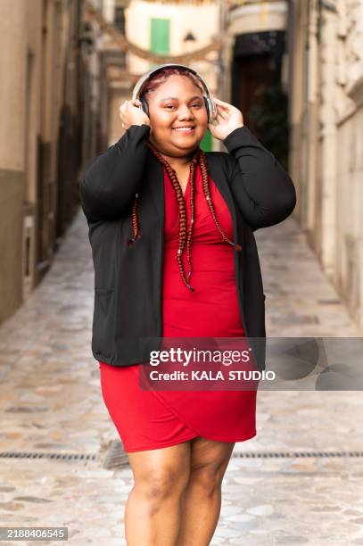 young woman listening music with headphones in the city - voluptuous stock pictures, royalty-free photos & images
