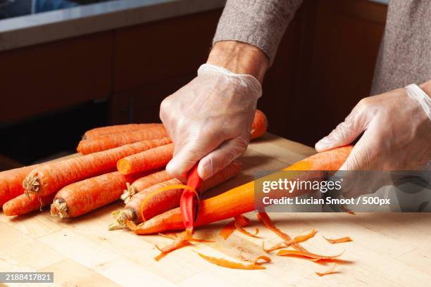 close-up of hands peeling carrots on wooden table,san diego,california,united states,usa - reinheit stock-fotos und bilder