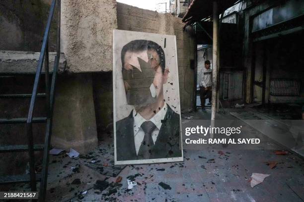 Defaced portrait of ousted Syrian president Bashar al-Assad stands in a ransacked government security facility, in Damascus, on December 8, 2024....