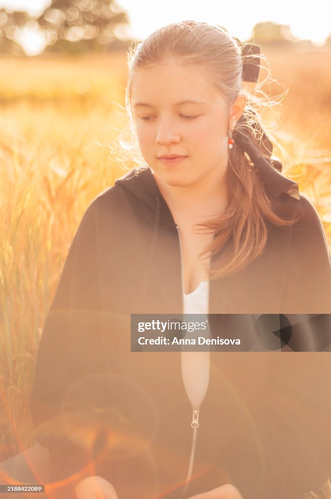 Young girl in golden wheat field during sunset