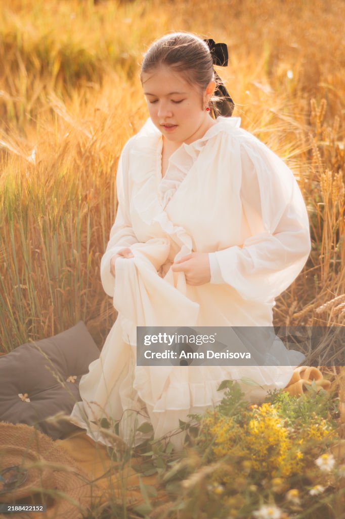 Young girl in golden wheat field during sunset