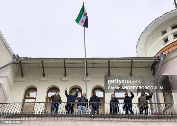 Demonstrators react after raising a Syrian opposition flag at the Syrian embassy in Moscow on December 9, 2024. A group of men at the Syrian embassy...