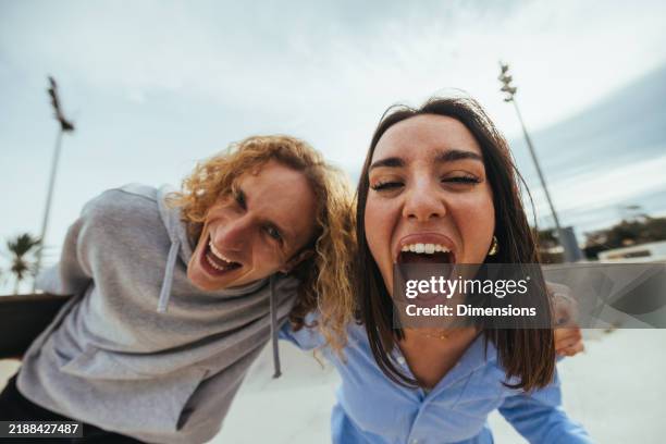 pareja joven divirtiéndose y gritando juntos en el skatepark - gran angular fotografías e imágenes de stock