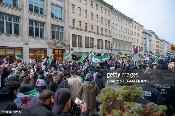 People waving the Syrian opposition's revolution flag gather to celebrate the collapse of Bashar al-Asad and the Syrian government during a rally in...