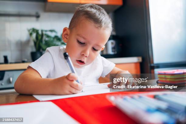 concentrated child boy 4 years old draws with felt-tip pens while sitting at home at the table - 4 5 years stock pictures, royalty-free photos & images