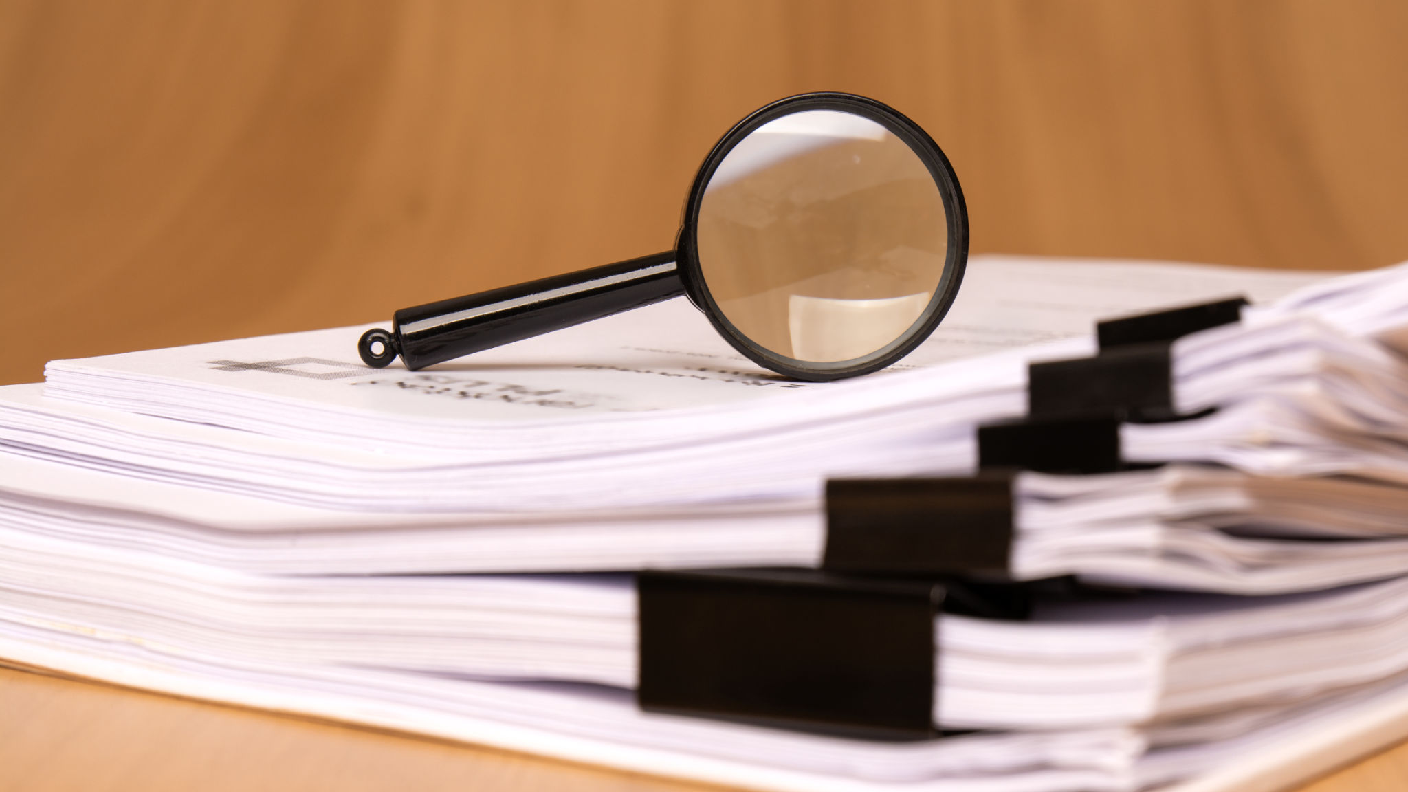 A Magnifying Glass That is Positioned on a Stack of Papers, Which are Secured by Clips A Magnifying Glass That is Positioned on a Stack of Papers, Which are Secured by Clips