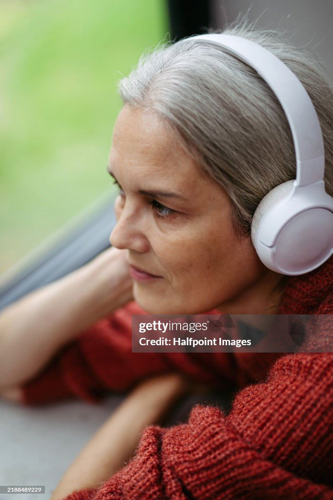 Woman listening relaxing or ambient music, looking out of window. Guided meditation.
