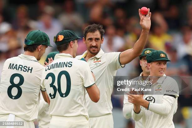 Mitchell Starc of Australia celebrates with teammates after dismissing Harshit Rana of India, his fifth wicket of the innings during day one of the...