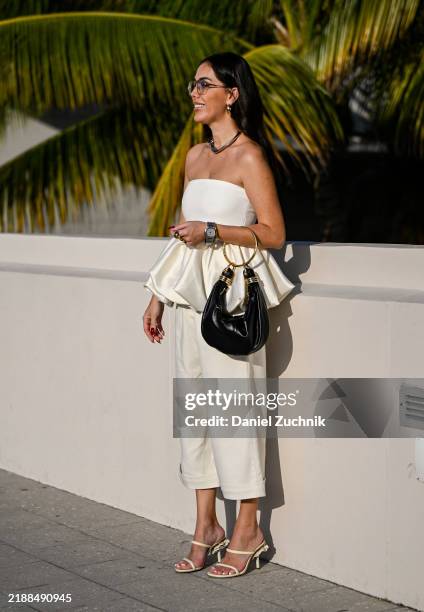 Olga Sokolenko is seen wearing a white jacket, white puff top, white slacks, white shoes and black and gold bag on December 05, 2024 in Miami,...