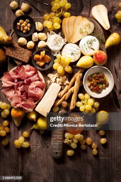 wood board of appetizer to share with cured meat, cheese and fruits, jam, hazelnut - antipasto stock pictures, royalty-free photos & images