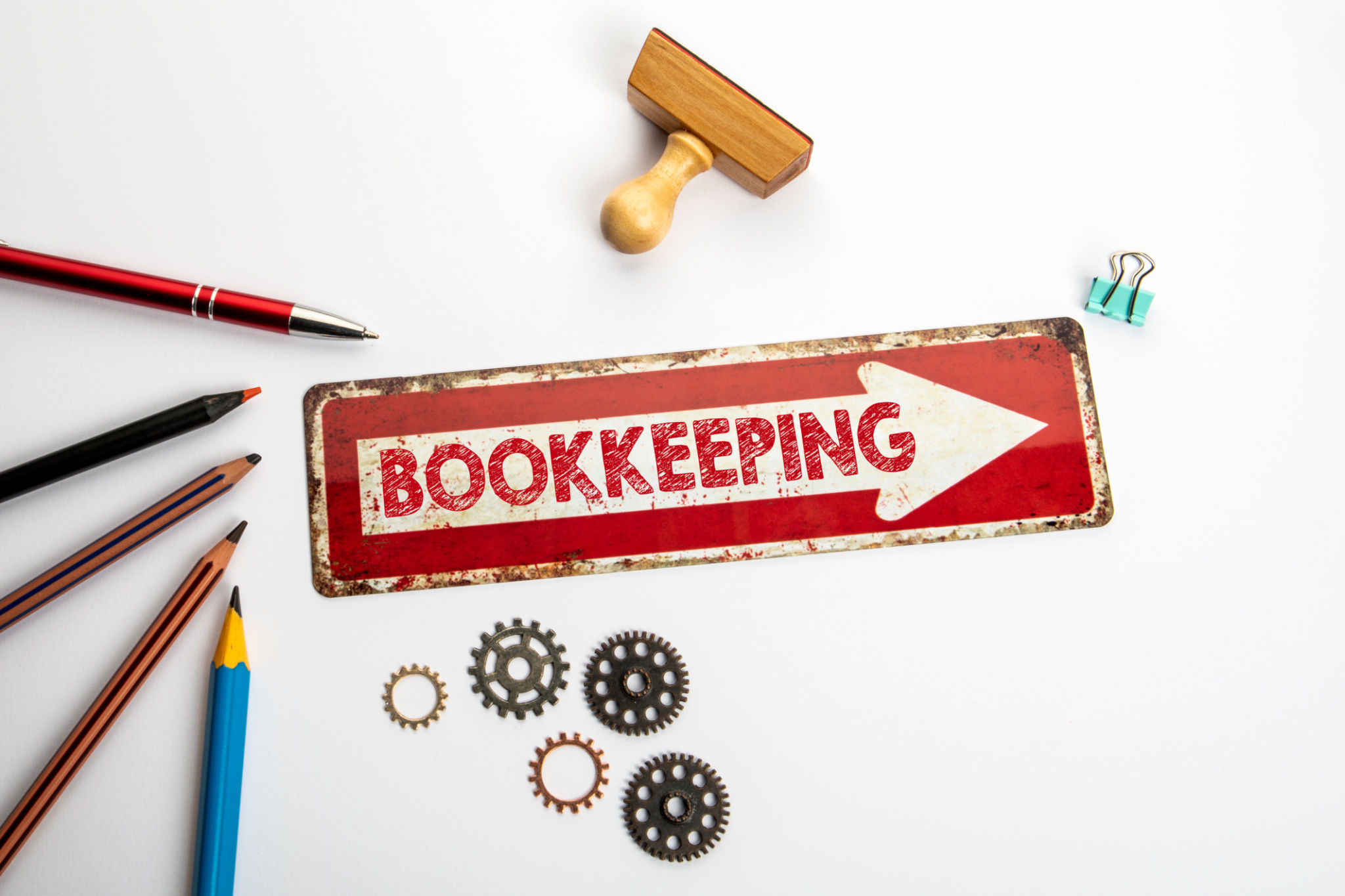 Bookkeeping. Red direction arrow with text on white office desk Bookkeeping. Red direction arrow with text on white office desk