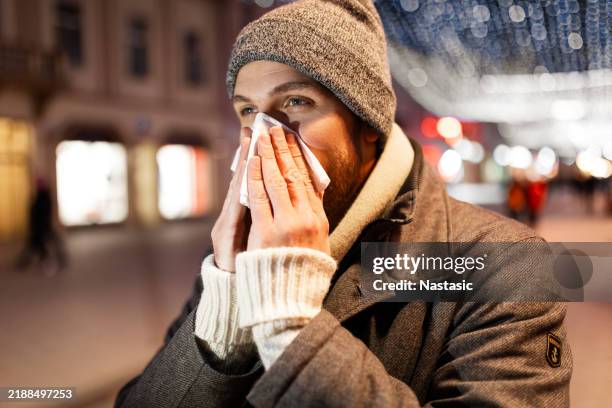 young man fighting a cold while walking outside - cold virus stock pictures, royalty-free photos & images