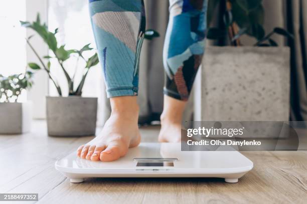close-up of bare feet stepping onto a digital scale, symbolizing health, fitness, and mindfulness in a modern home setting - balance photos et images de collection