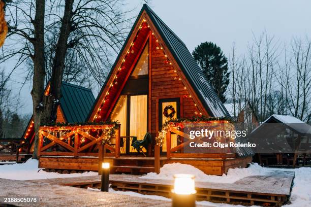 cozy a-frame cabin glowing with christmas lights in winter wonderland - chalet stockfoto's en -beelden
