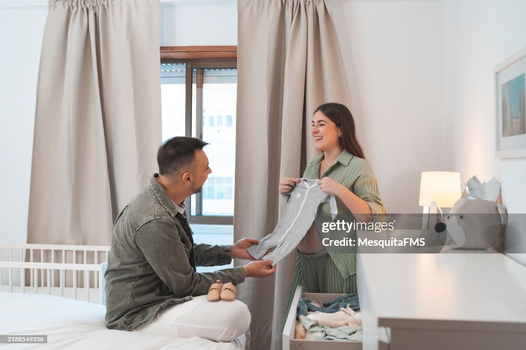 赤ちゃんの服の引き出しを見ている妊娠中のカップル