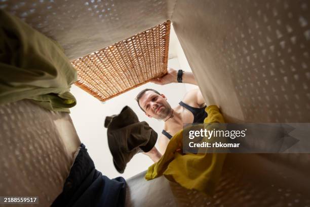 man sorting laundry viewed from inside a hamper - throwing clothes stock pictures, royalty-free photos & images