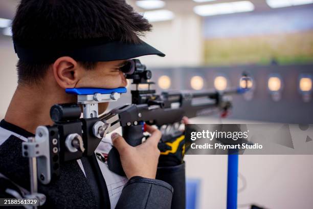 präzisionsschießsportler auf einem indoor-schießstand - sportschießen stock-fotos und bilder