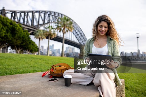 Woman working outdoors on her tablet in Sydney while drinking coffee Woman working outdoors on her tablet in Sydney while drinking coffee
